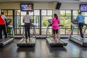 A gym with treadmills, large windows, and TVs displaying news. - Jacaranda (Nairobi)