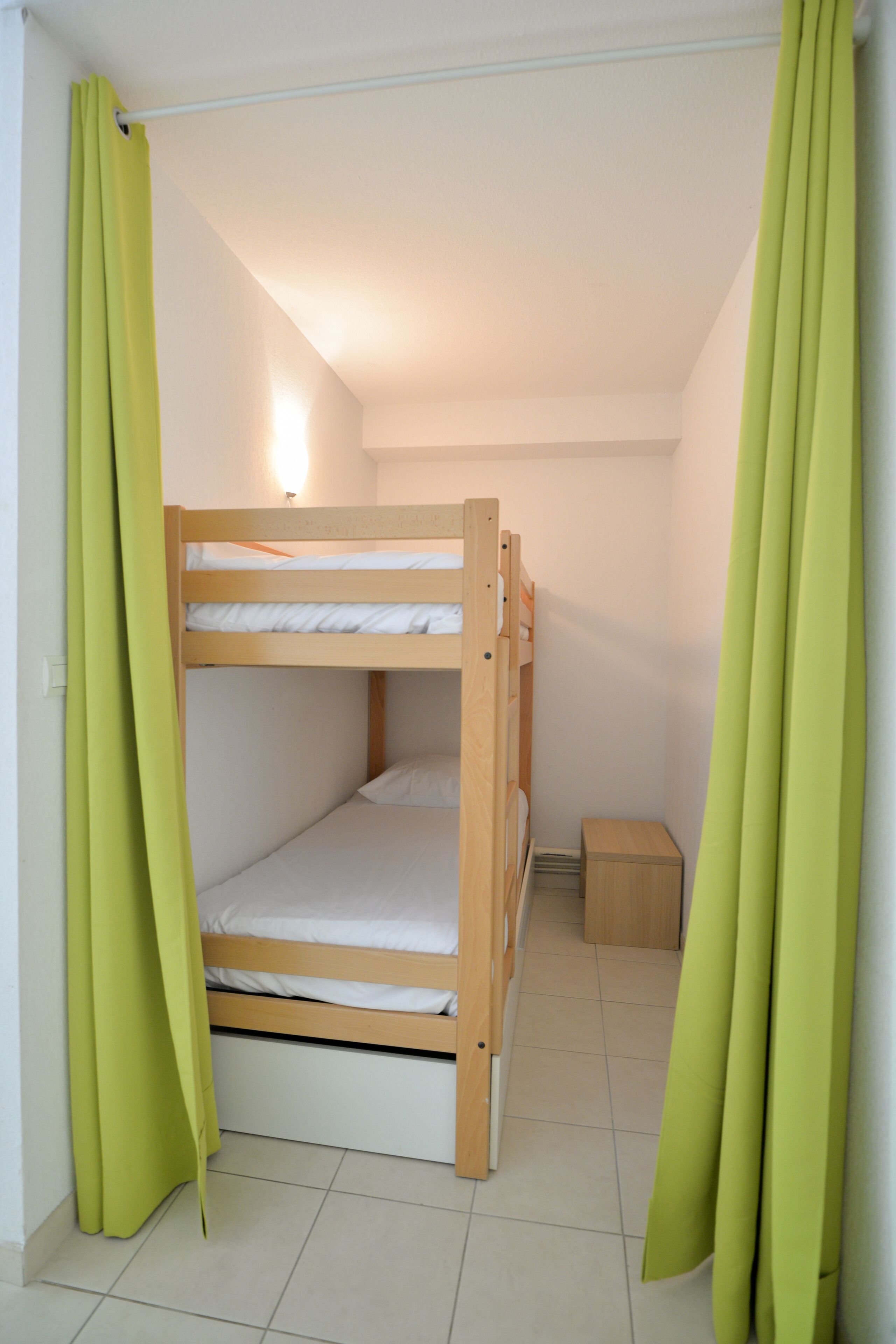 A bunk bed room with a small wooden cabinet and a light fixture.
