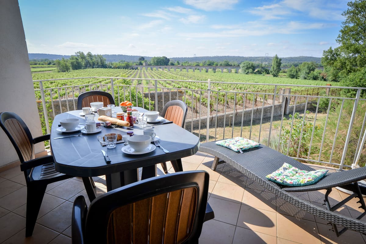 A terrace with a table set for breakfast, overlooking a vineyard.