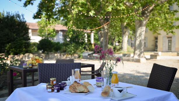 Mesa de comedor al aire libre con comida, bebidas y salsas.