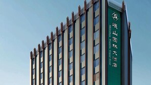 Un edificio de hotel alto con un diseño moderno, destacando un letrero vertical verde con caracteres chinos.