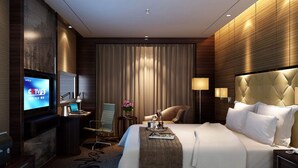 Habitación de hotel moderna con una cama grande, televisión, escritorio con silla, mesita de noche y lámpara.