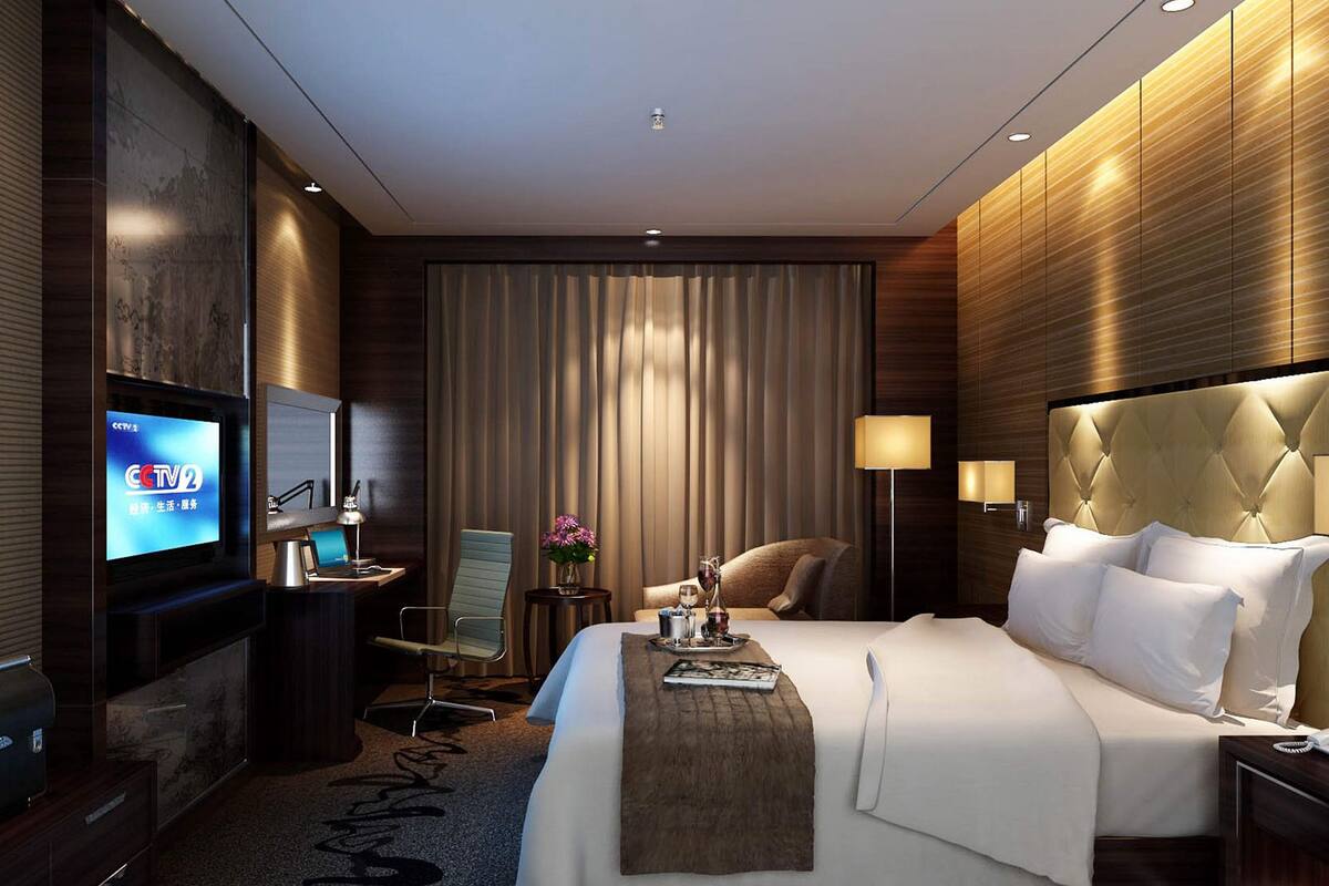 Habitación de hotel moderna con una cama grande, televisión, escritorio con silla, mesita de noche y lámpara.