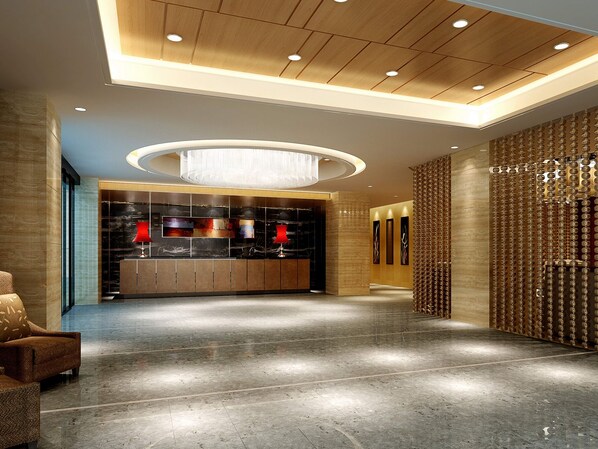 Eine geräumige Lobby mit einem modernen Kronleuchter, einem Empfangsbereich und einer Wand mit einem besonderen Muster.