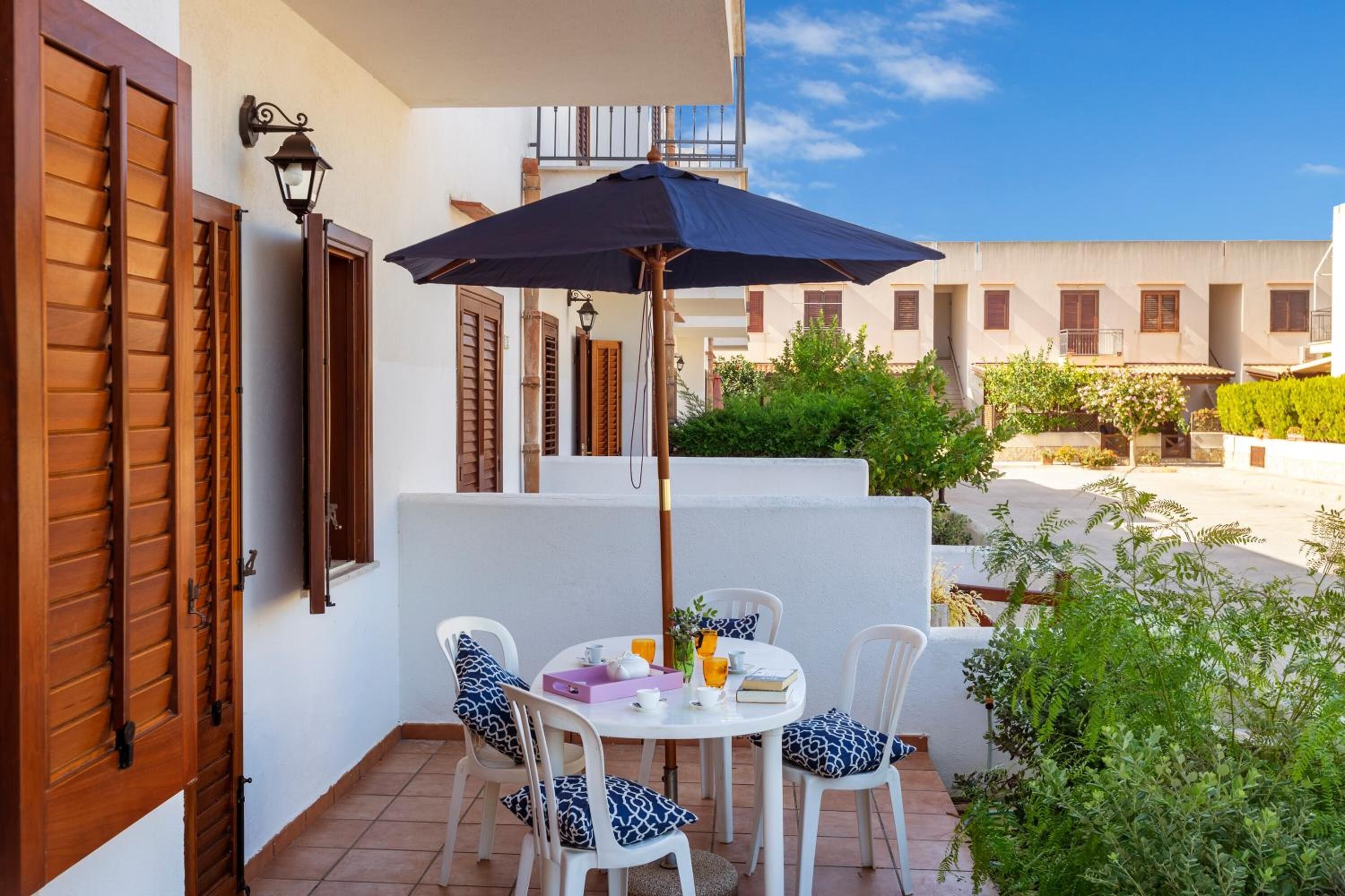 Une terrasse avec une table, des chaises et un grand parasol.