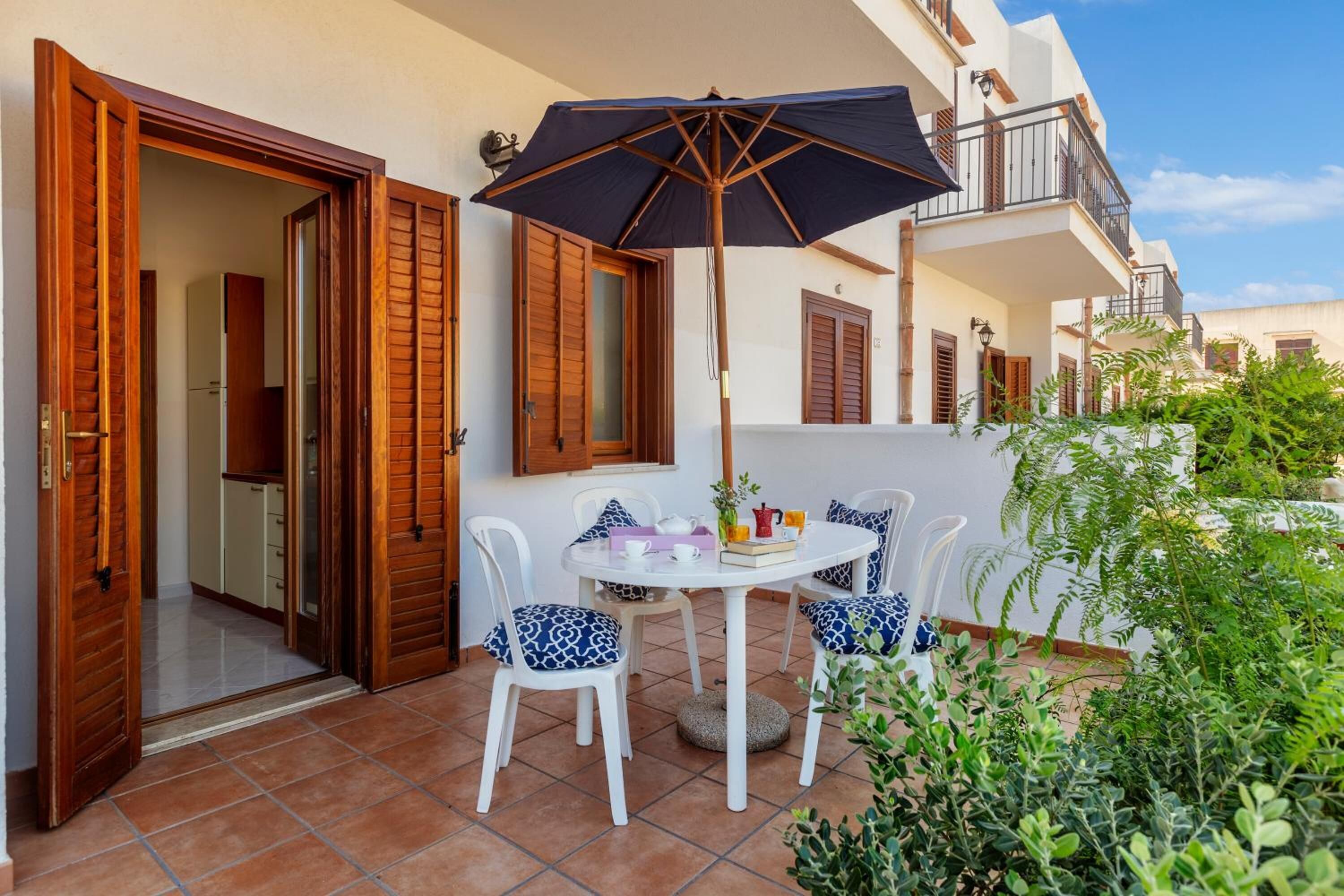 A patio with a table, chairs, and an umbrella.