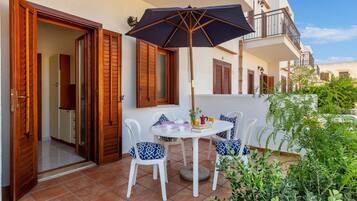 A patio with a table, chairs, and an umbrella.