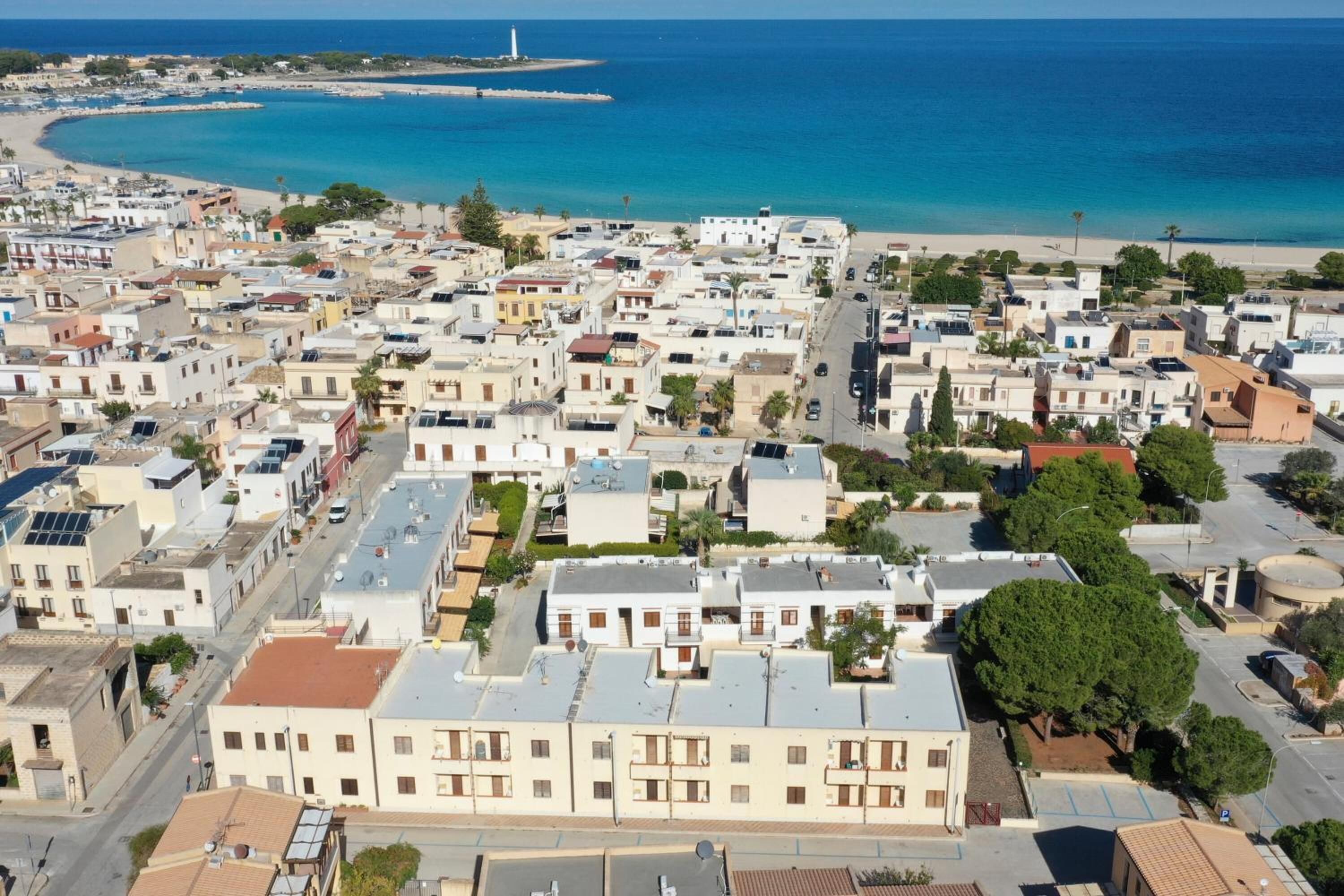 A coastal town with a mix of residential buildings and a beach in the background.