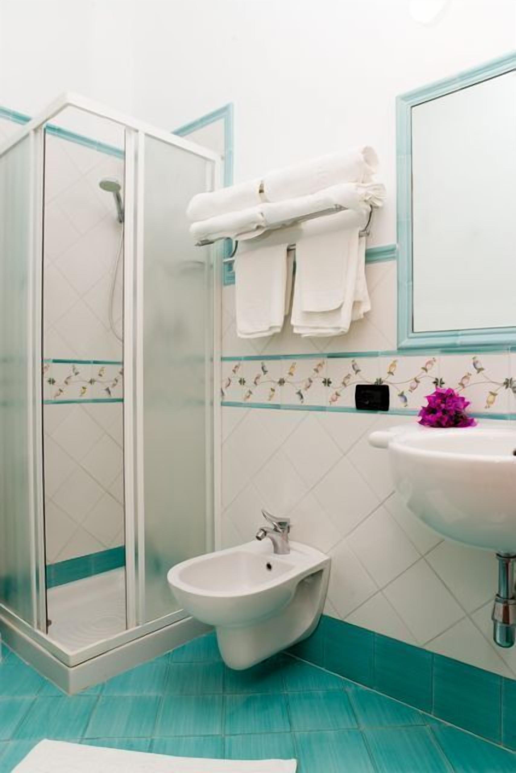 A bathroom with a shower, bidet, and sink.