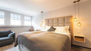 A modern bedroom with a large bed, bedside tables, a desk, and a sofa.