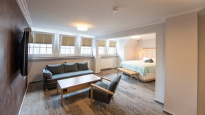 A compact, well-lit room with a sofa, a small table, a chair, and a bed. - Ratshotel (Haltern am See)