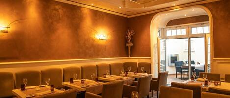 Un restaurante con cabinas y mesas, iluminación cálida y vista al salón comedor.