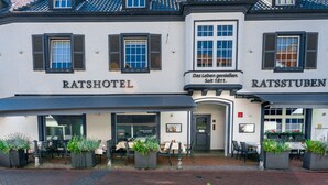 A traditional Ratshotel building with a classic facade, large windows, and outdoor seating area with potted plants. - Ratshotel (Haltern am See)