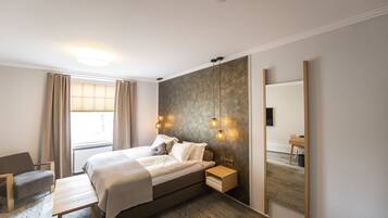 Quarto moderno com cama grande, mesas de cabeceira, escrivaninha e espelho.