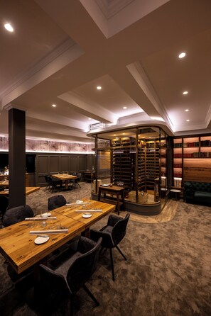 A conference room with a long table, chairs, and a glass partition with bookshelves. - Ratshotel (Haltern am See)
