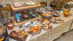 A buffet table with various food items, including bread, pastries, and a meat display.