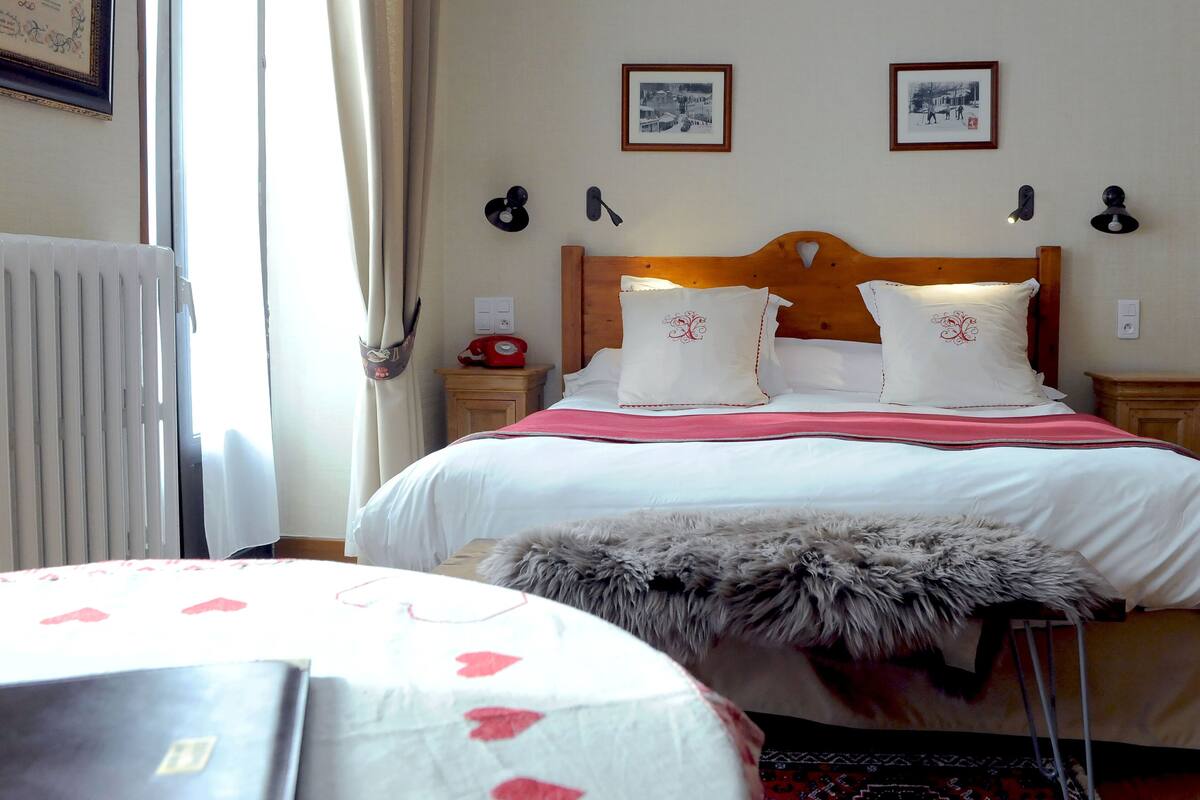 Habitaci ón de hotel con cabecera de madera, dos lámparas de noche, un teléfono rojo y una alfombra mullida.