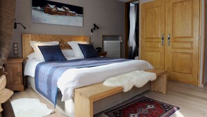 A bedroom with a large bed, wooden headboard, bedside tables, a nightstand, a radiator, and a wardrobe.