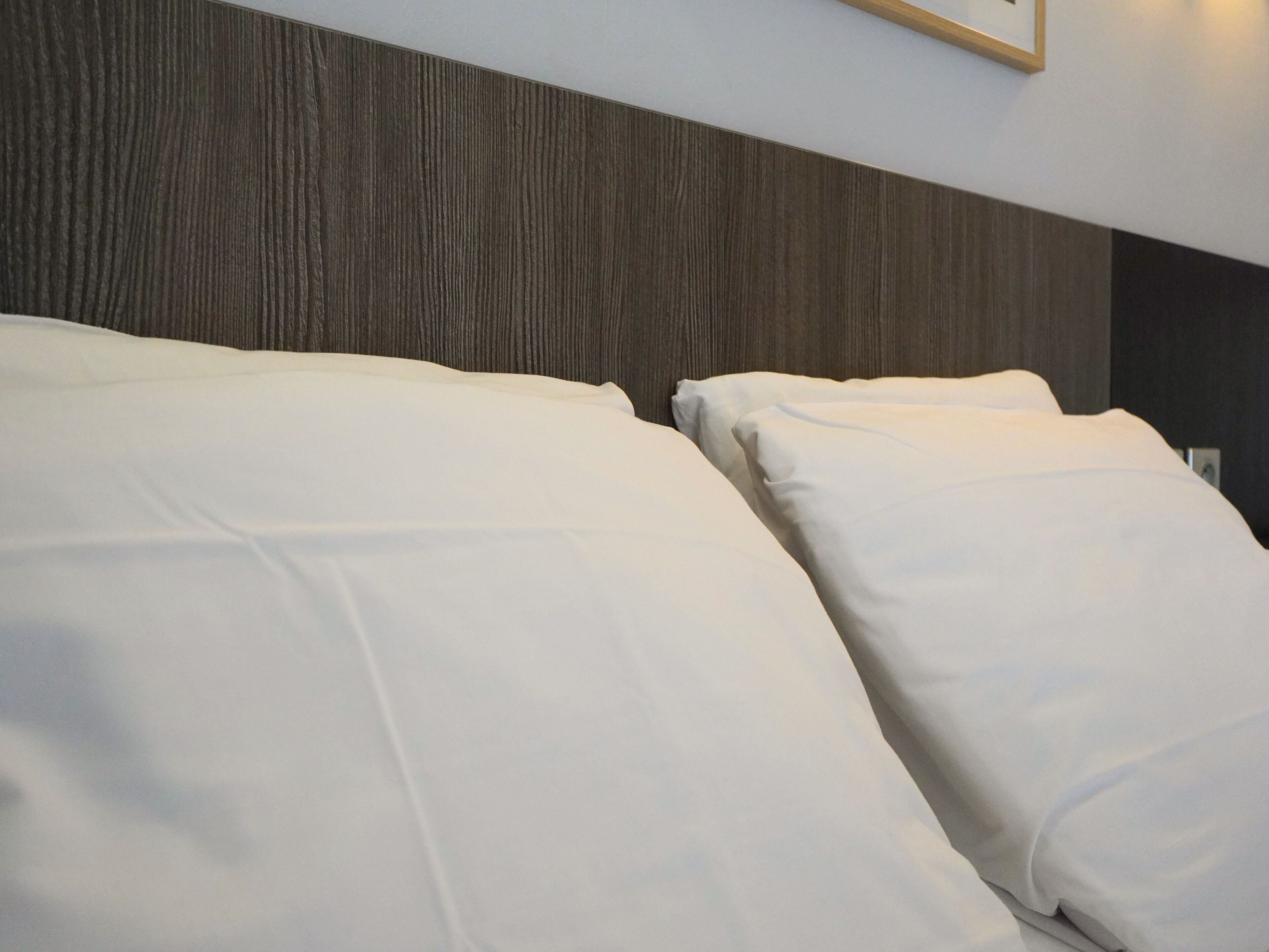 A bed with white bedding and a wooden headboard.