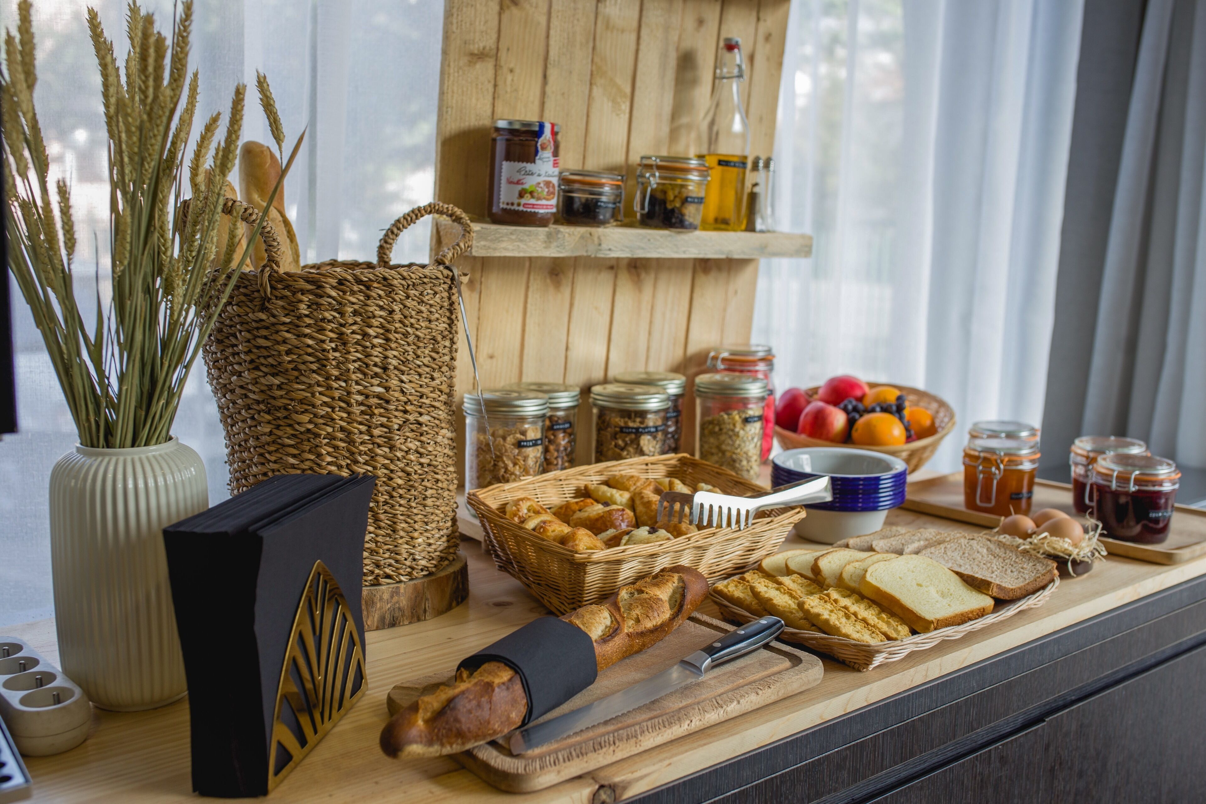A breakfast buffet with bread, pastries, fruits, and condiments.