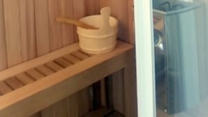 A sauna room with wooden walls, a bench, and a wooden rack. - Hôtel Sable et Soleil (Fréjus)