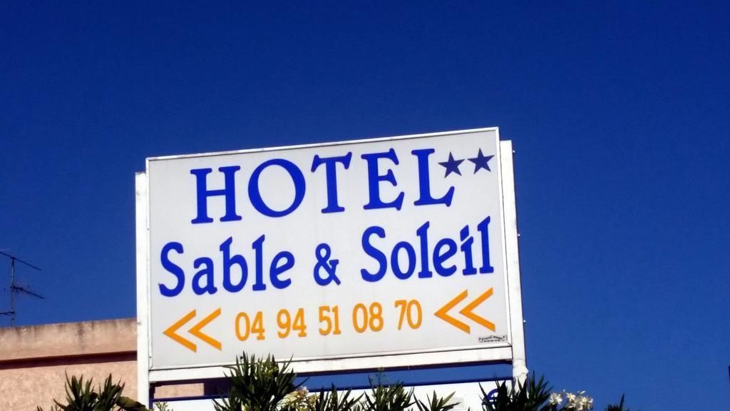 A hotel sign with the name "Sable & Soleil" and a phone number.
