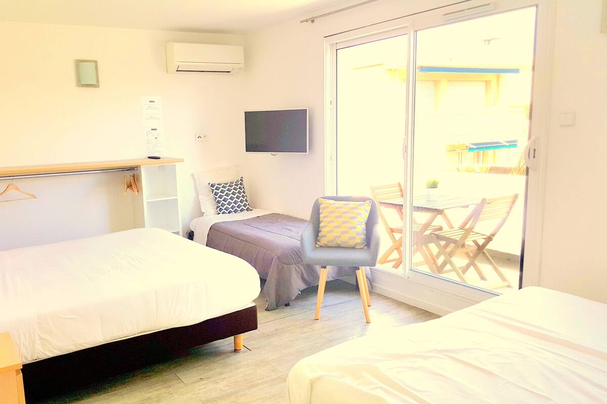 A hotel room with a bed, a desk, a chair, and a sliding glass door leading to an outdoor area.