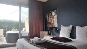 A modern bedroom with a large bed, a view of the outdoors, and a painting on the wall. - Hôtel Sable et Soleil (Fréjus)