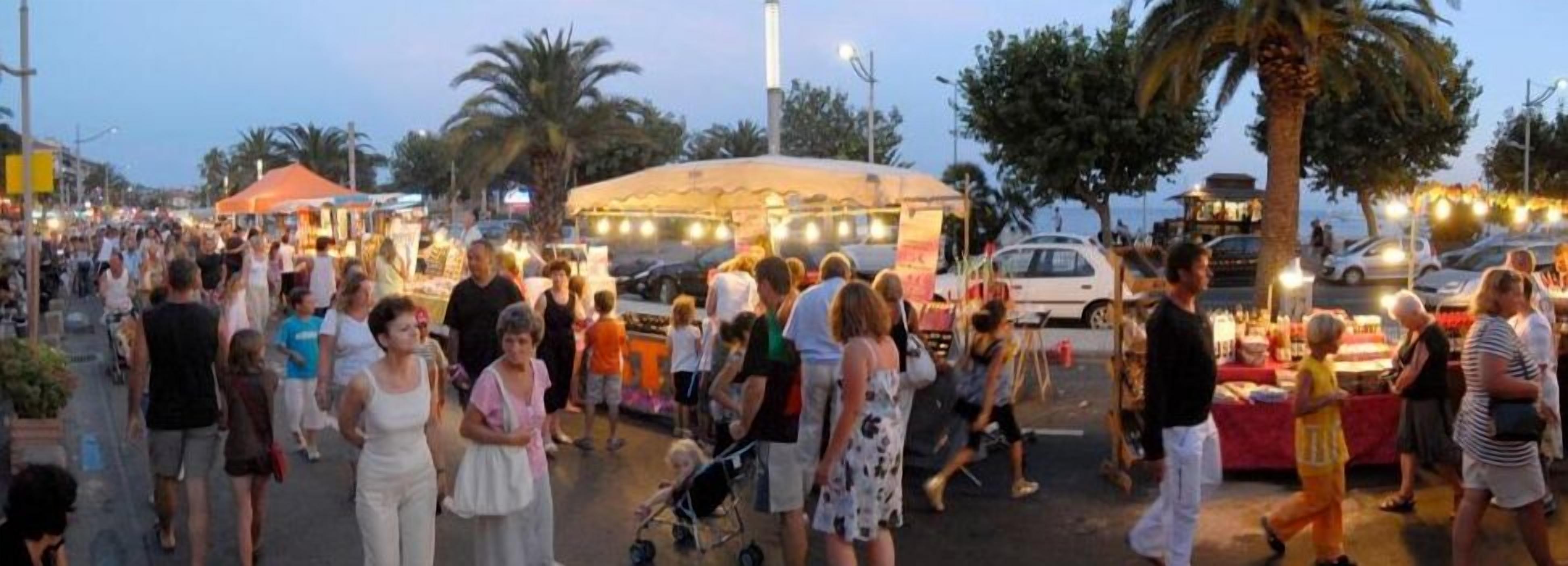 Un mercato all'aperto affollato, con numerosi banchi e persone che passeggiano.