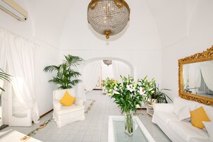 Una habitación amplia con candelabro, muebles blancos y un espejo grande.