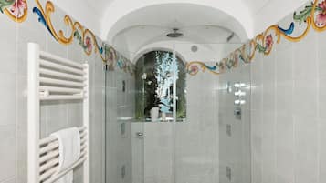 A modern bathroom with a glass shower enclosure, white tiled walls, and decorative floral patterns.