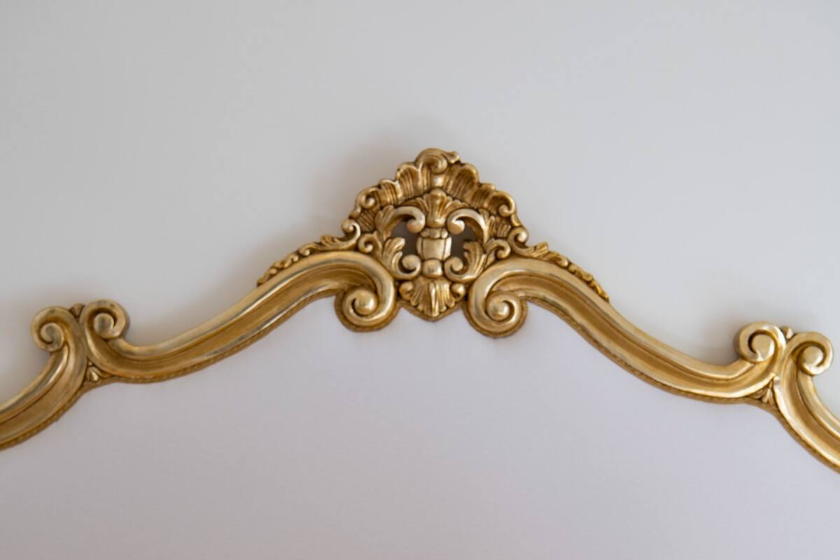 A bed with a gold ornate headboard and yellow and white pillows.