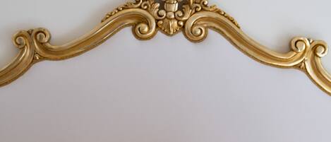 A bed with a gold ornate headboard and yellow and white pillows.