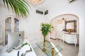 A modern living room with a glass coffee table, white sofa, and a white dresser with a mirror. - Villa Yiara (Positano)