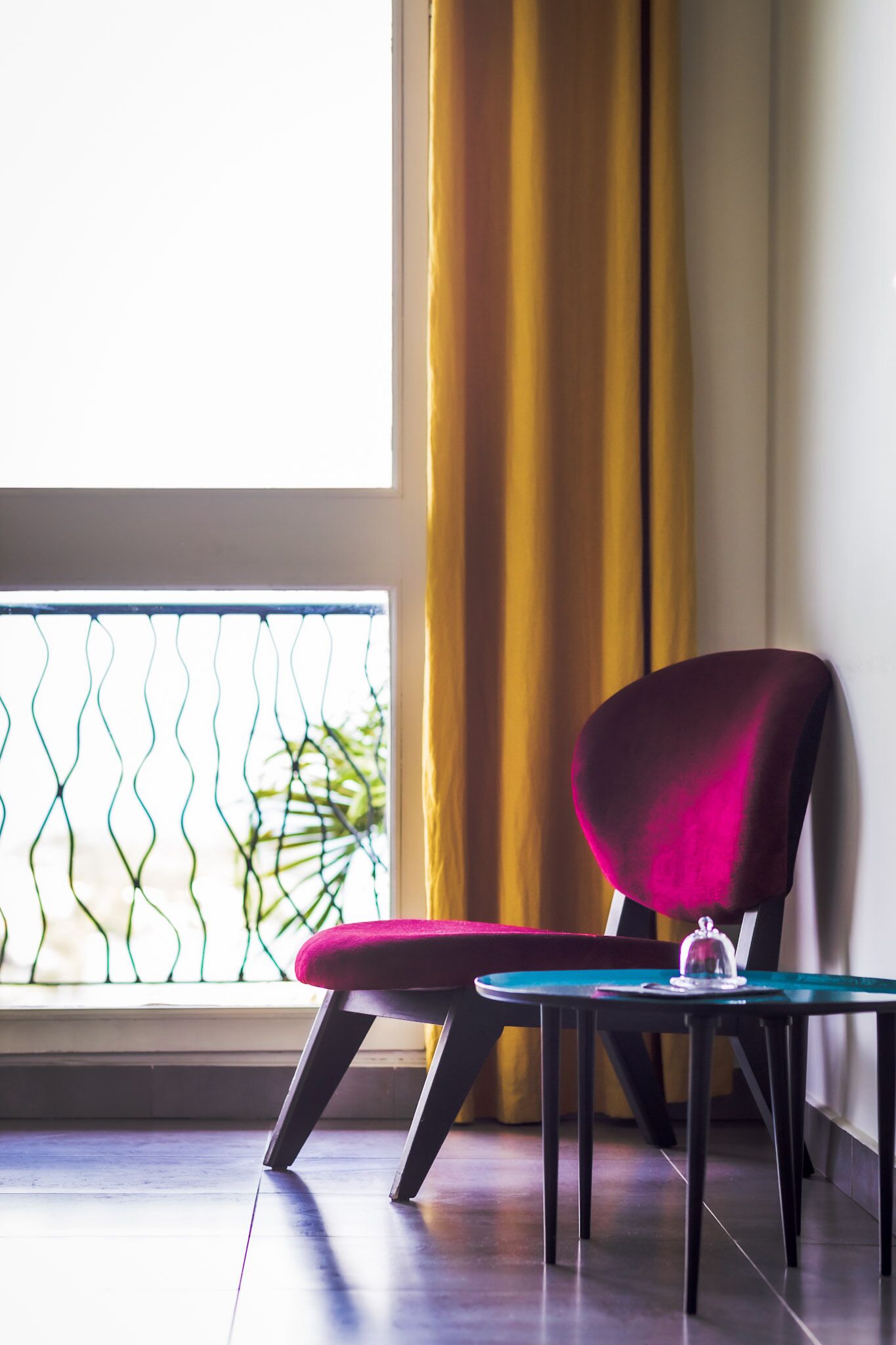 A room with a chair and a small table near a window with a curtain.