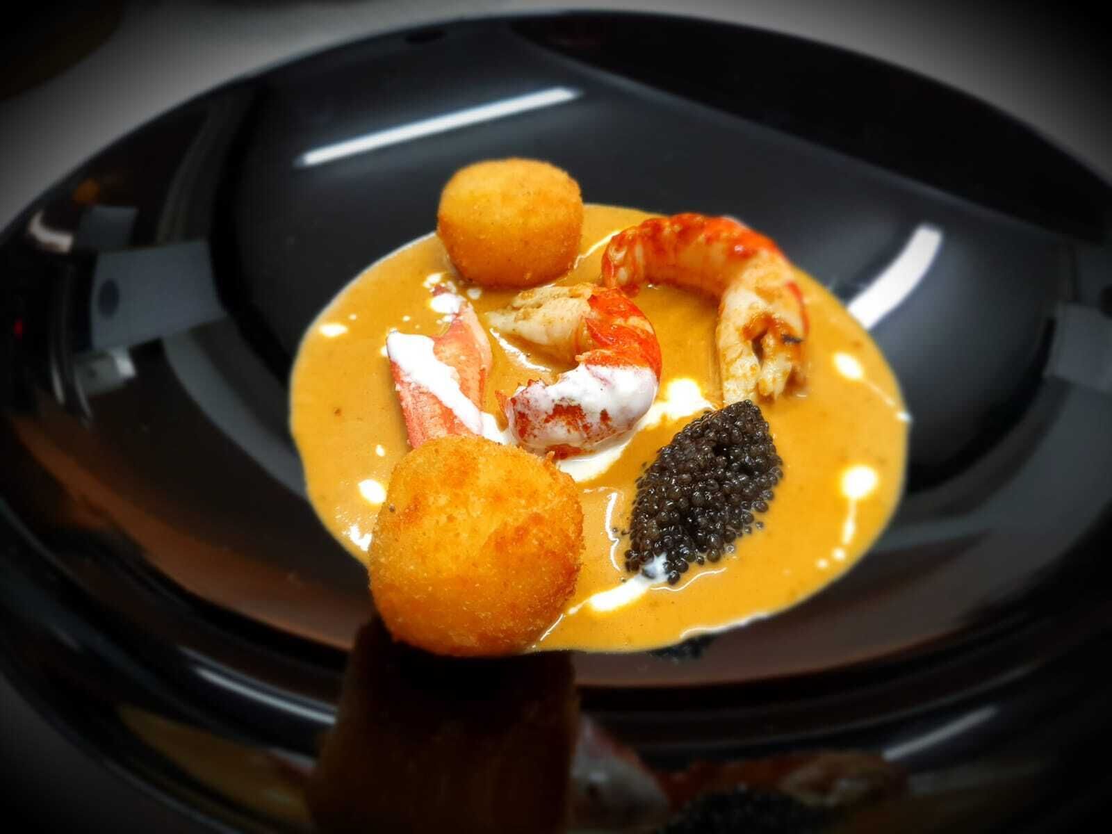 A dish with seafood and a spherical item on a black plate.