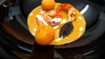 Un plato negro con mariscos y un elemento esférico.