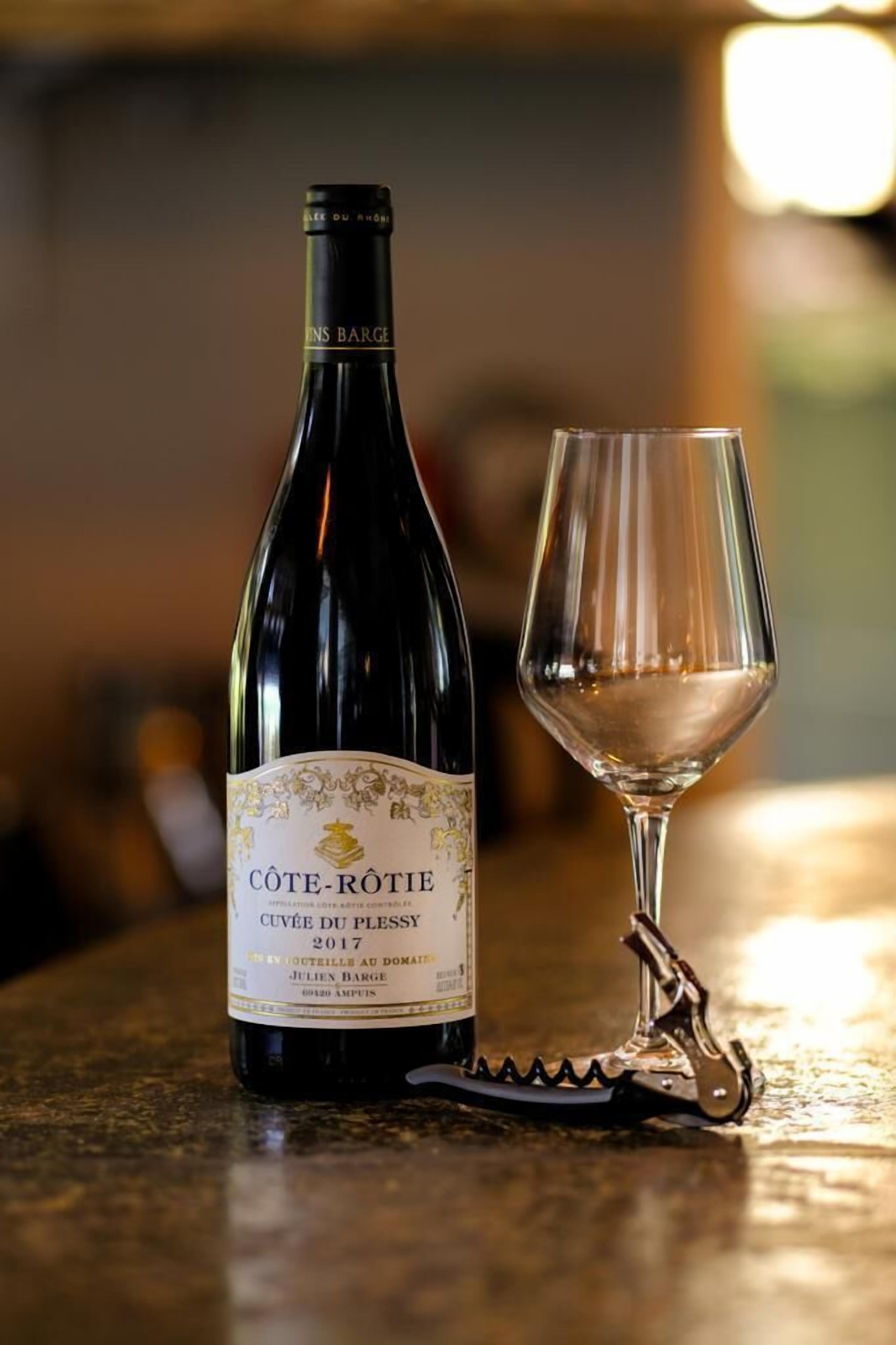 Une bouteille de vin de Côte-Rôtie et un verre à vin sur une table.