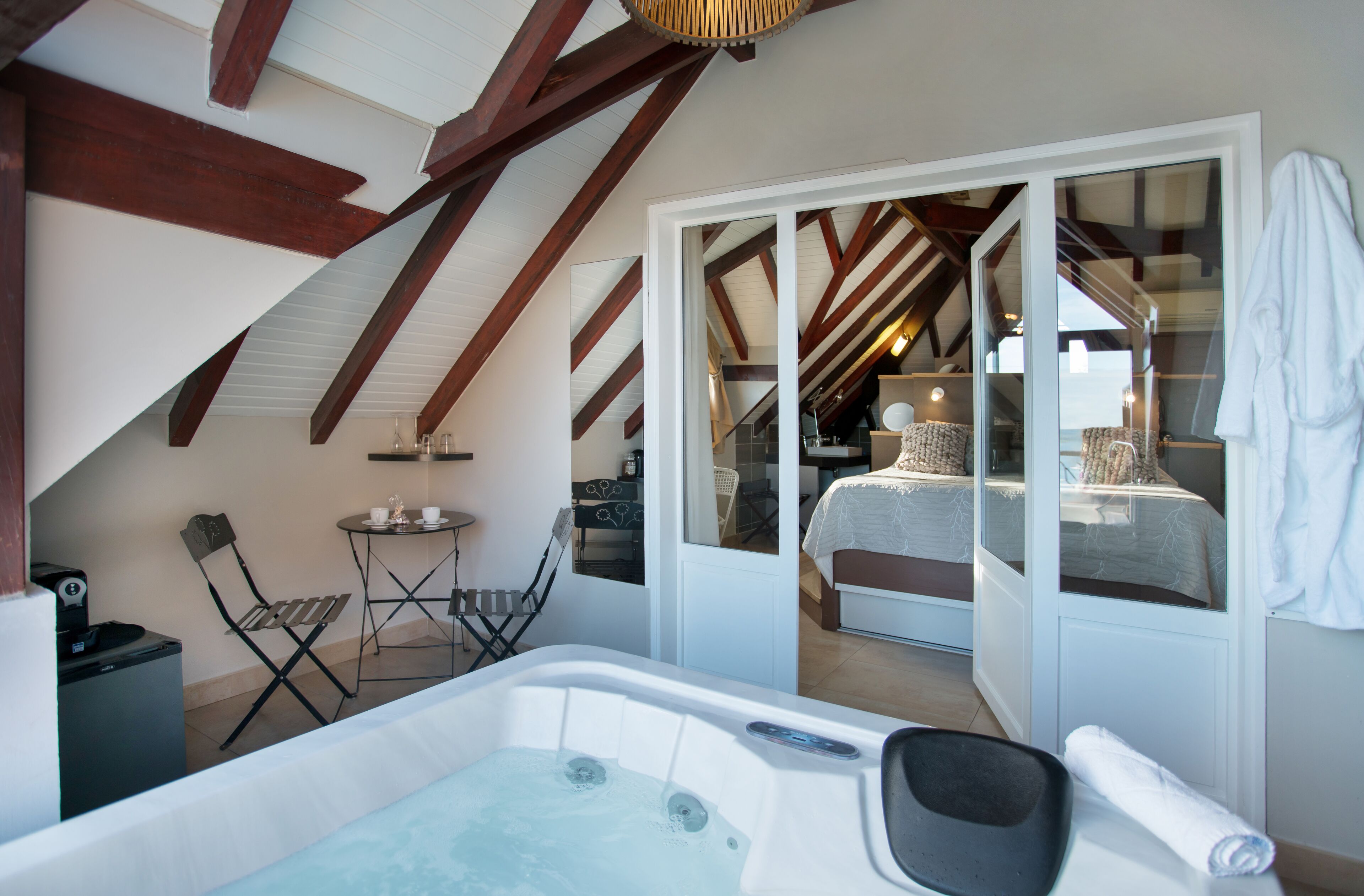 Un dormitorio acogedor en el ático con una cama grande, un jacuzzi y un balcón con vistas.
