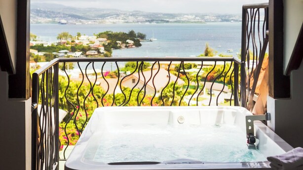 A hot tub with a view of a lake and surrounding landscape. - La Suite Villa (Trois-Ilets)