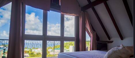 Une chambre avec une grande fenêtre, un lit et une vue sur l’extérieur.
