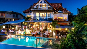A two-story building with a swimming pool in front, featuring outdoor seating and a bar area. - La Suite Villa (Trois-Ilets)