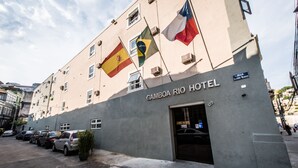 Exterior del Hotel Gamboa Rio, con varias banderas, un estacionamiento y vista a la calle.