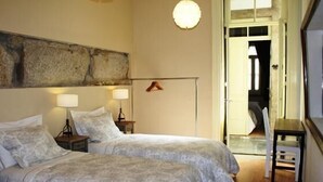 Une chambre avec deux lits, des lampes de chevet, une grande œuvre d’art abstraite au mur et une vue sur l’extérieur.