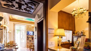 Un hall d’hôtel comprenant un comptoir d’accueil, un lustre, un téléviseur et un panneau indiquant un espace réservé aux services.