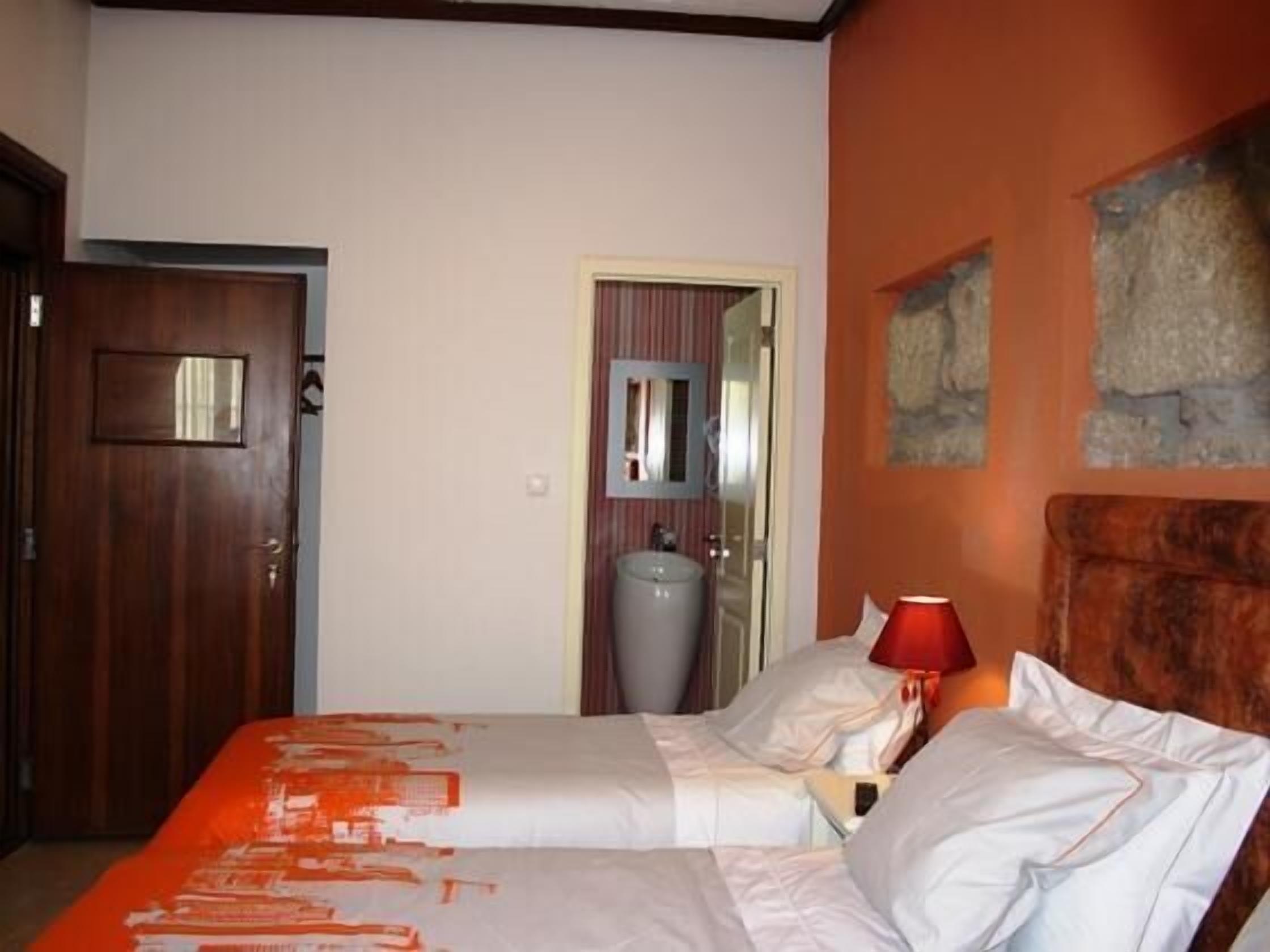 A hotel room with a bed, a nightstand, a lamp, and a mirror.