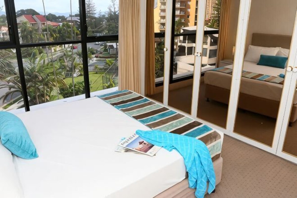 Habitación de hotel con una cama grande, un balcón con vistas y una zona de estar separada.