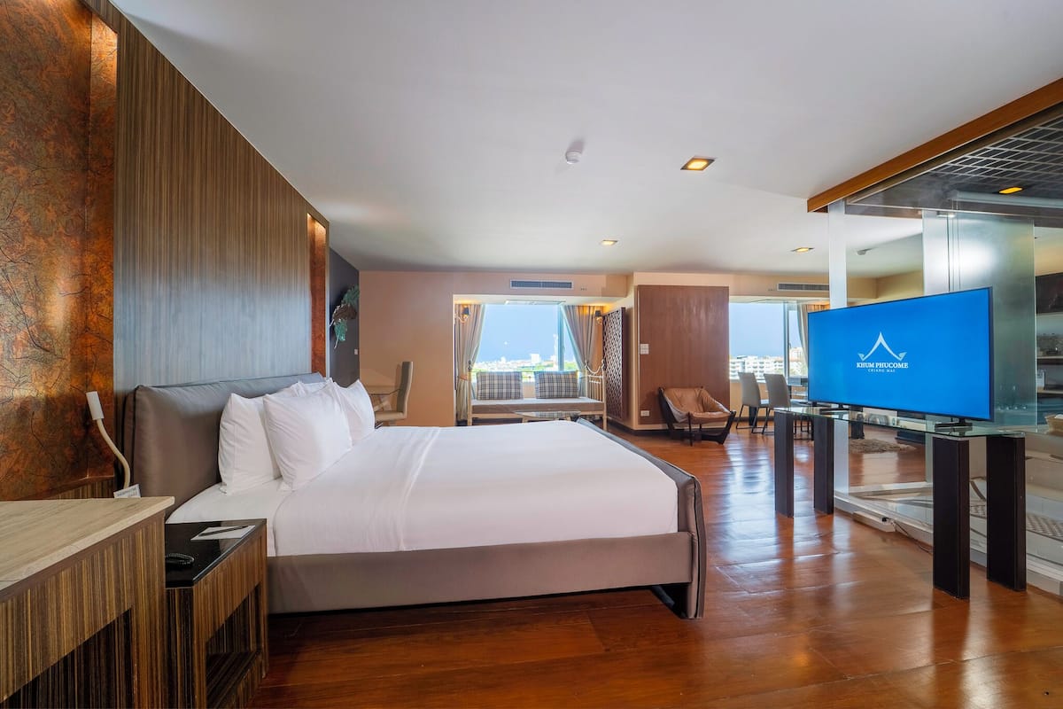 Een hotelkamer met een groot bed, een televisie, een bureau en uitzicht op de stad.