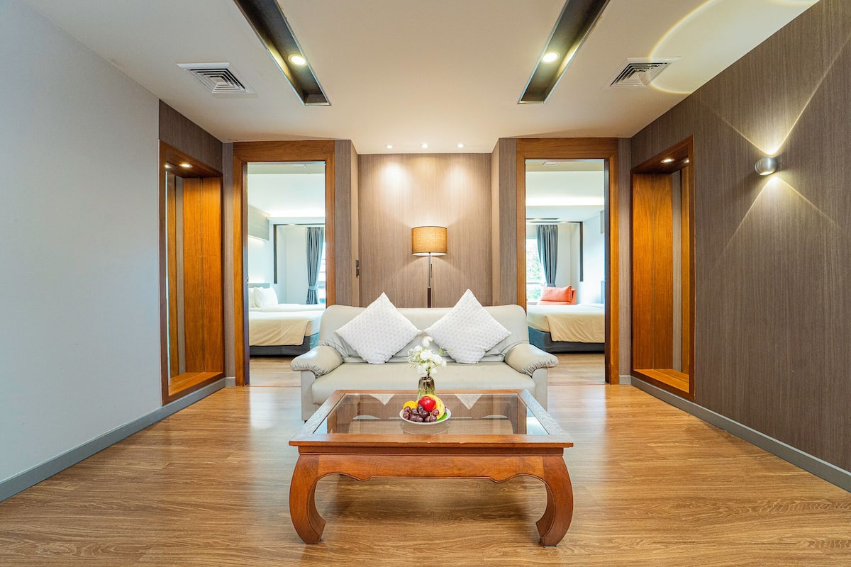 Een moderne hotelkamer met een bank, een bijzettafeltje met fruit, en een lamp.