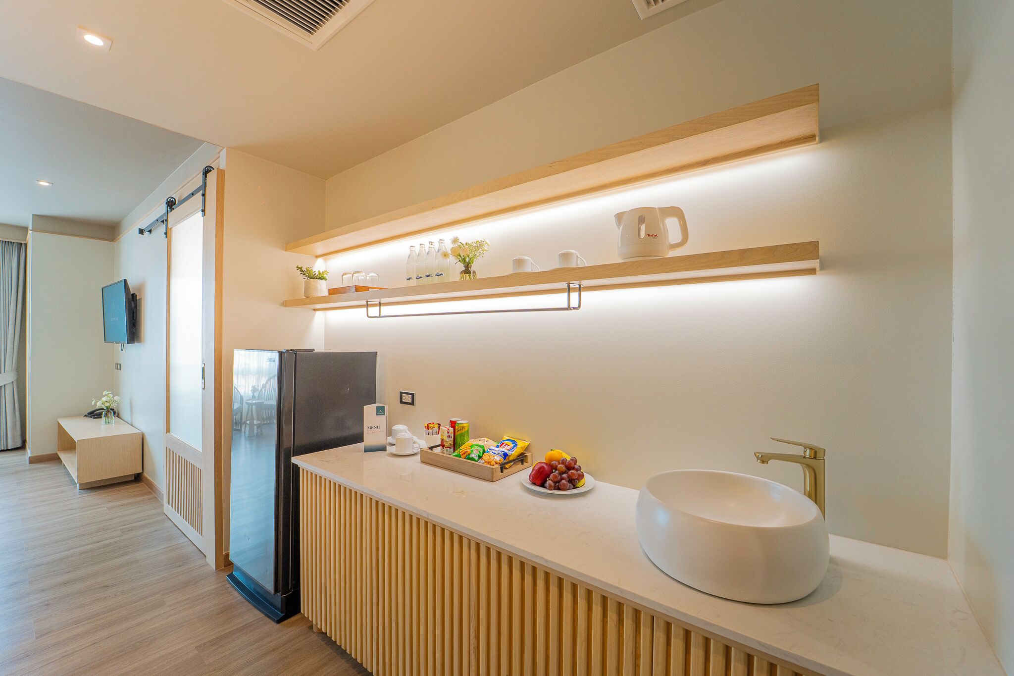 Una cocina moderna con refrigerador integrado, un lavamanos y una encimera con frutas y una cafetera.